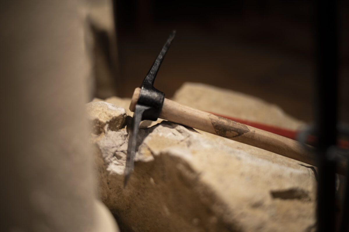 Ein Spitzhammer bearbeitet einen rauen Stein